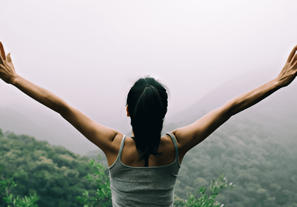 Person with arms raised in forest